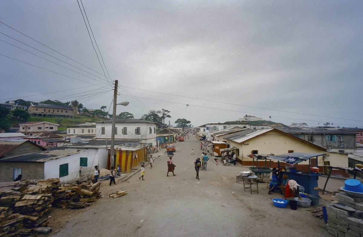 EU: Elmina, Dutch Cemetery Road street view with Fort St. Jago on hill (2000), Elmina, Ghana, 2000