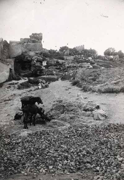 EU: Fez, Morocco: the path to Bab Ghissa with ruins in the background and donkeys and cloaked figures in the foreground. Photograph, (1922), Fes, 1922