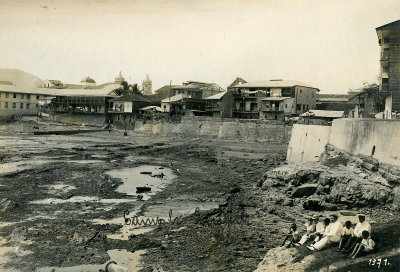 EU: Panama-Stadt. Drei Touristen der Hapag mit einheimischen Kindern auf Felsen vor ausgetrocknetem Hafenbecken oder Bucht sitzend (1915), Panama City, 1915
