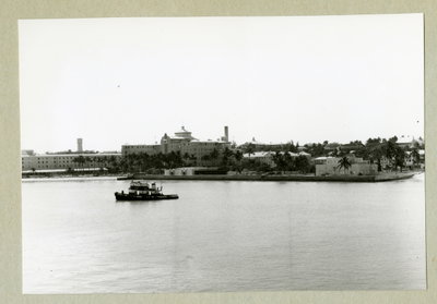 EU: Bilden föreställer en stadsvy av Bahamas huvudstad Nassau med bebyggelse och växtlighet. Framför staden syns ett fartyg. Bilden är tagen under minfartyget Älvsnabbens långresa (1966), Nassau, 1966