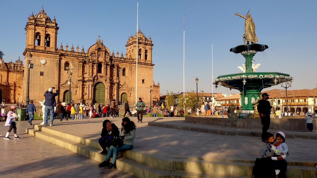 En el ajetreo diario, la Catedral del Cusco se alza majestuosamente junto a la pileta de la plaza, iluminada por los cálidos tonos del atardecer, Cusco, Peru, 2022