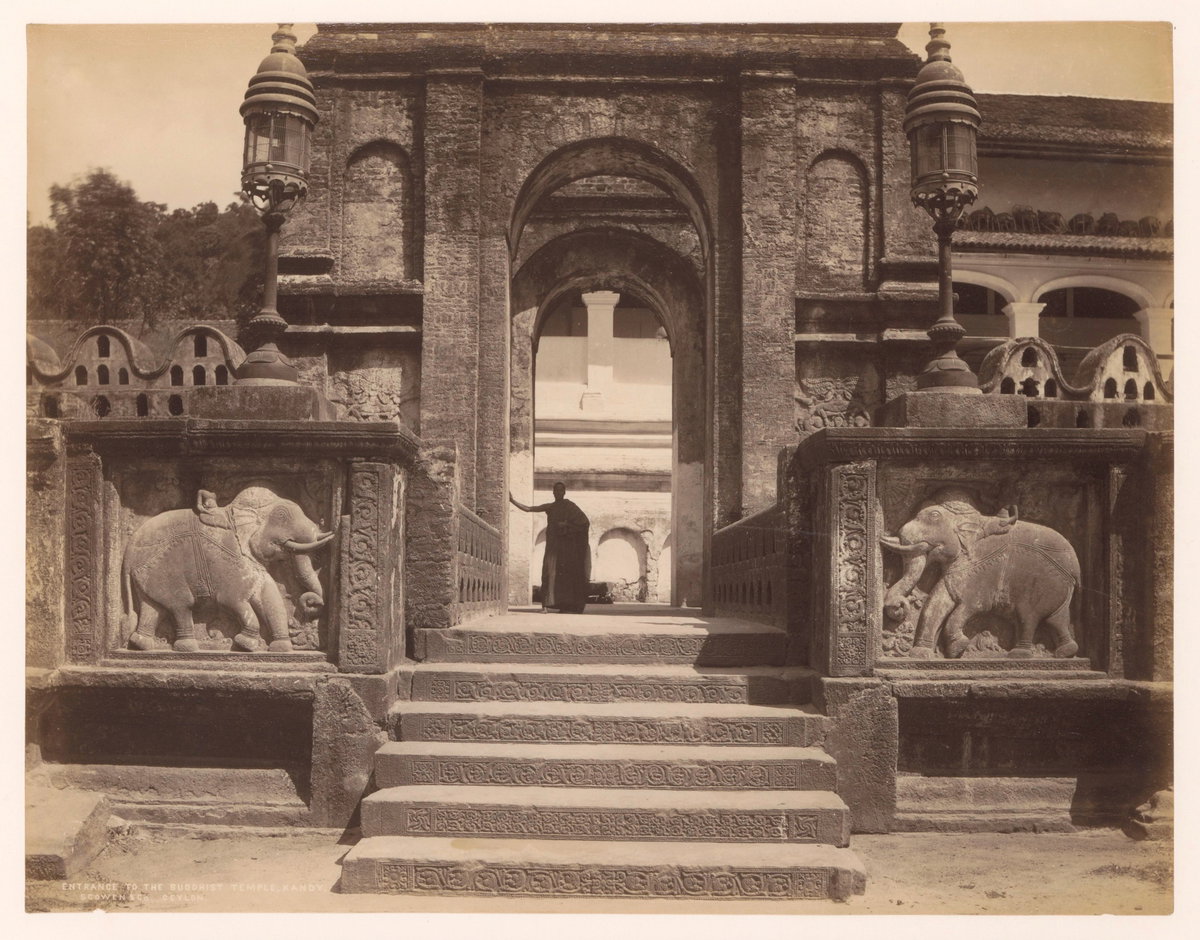 Toeganspoort tot een boeddhistische tempel, in de ingang staat een monnik Entrance to the Buddhist temple, Kandy. Ceylon (titel op object), Kandy, Sri Lanka, 1875