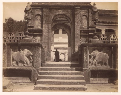 Toeganspoort tot een boeddhistische tempel, in de ingang staat een monnik Entrance to the Buddhist temple, Kandy. Ceylon (titel op object), Kandy, 1875